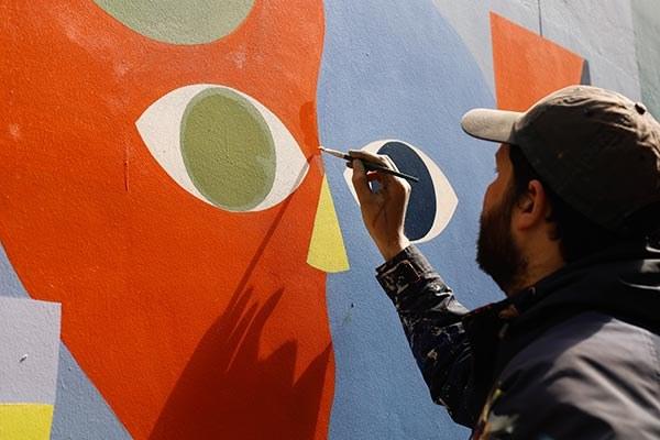 Un des artistes en train de peindre la fresque Ropsodie