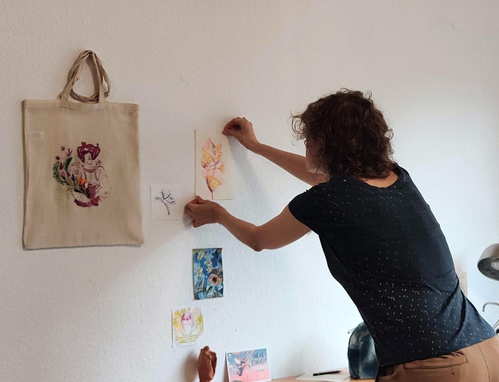 Marine accroche ses oeuvres sur les murs de son atelier 