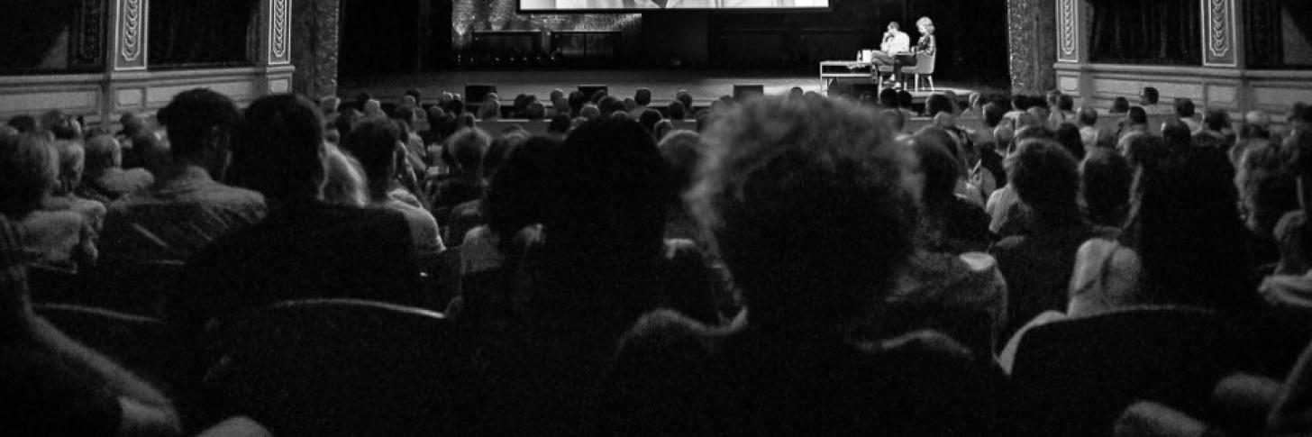 Photo de la scène et du public de dos  - Photo par MV Gillard